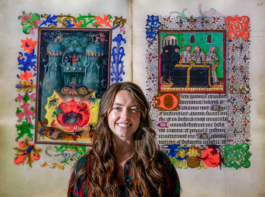 Student standing in front of a large manuscript