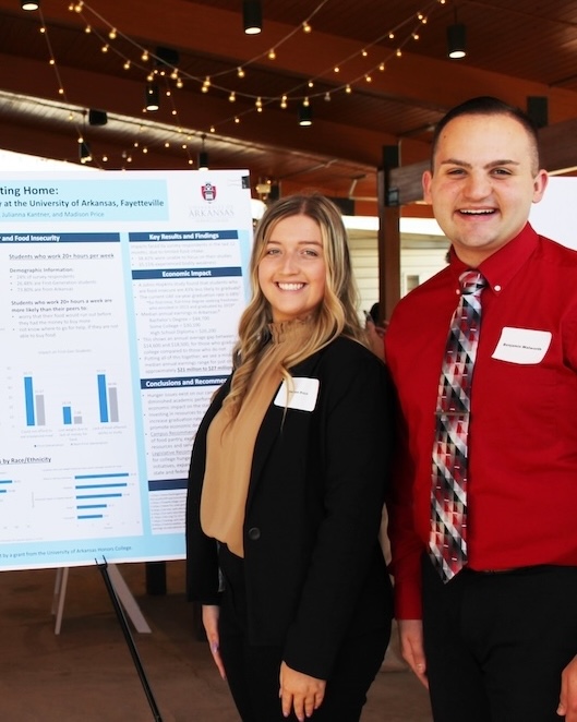 Students standing next to their research poster on food insecurity on campus.